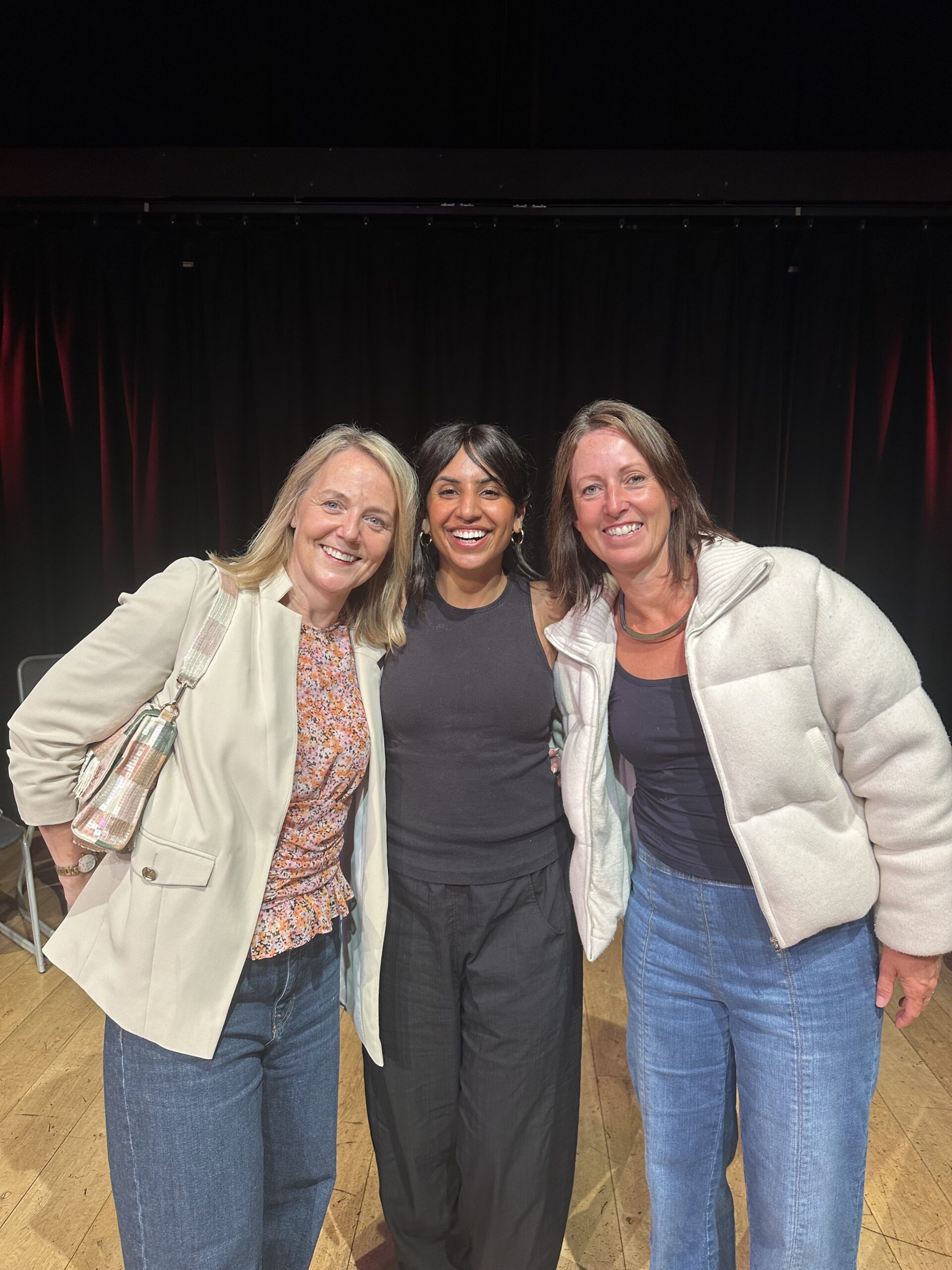 Marianne Smith of AD:VENTURE, Prab Riat of Think Fast Collective and Sophie Seddon, of Sophie Seddon PR smiling together on stage after Murder Inc's improvised murder mystery event at Seven Arts, Leeds.